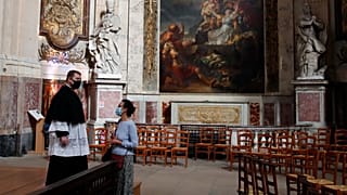 Un prêtre parle avec une croyante avant une message en l'église Saint Roch à Paris, le 23 mai 2020