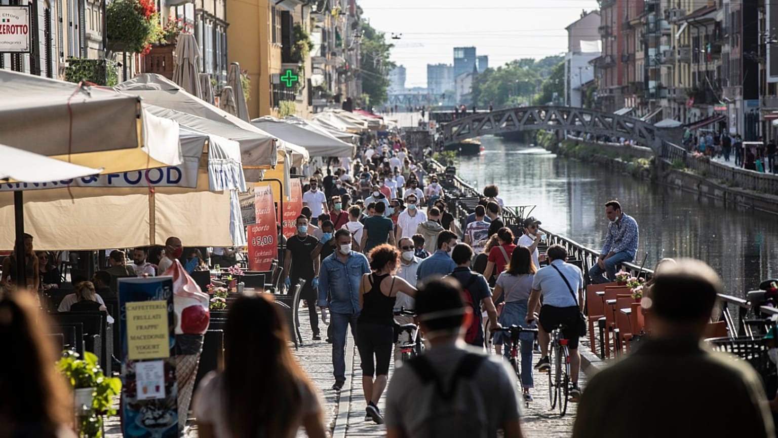 Des promeneurs profitent du soleil le long du canal Naviglio Grande à Milan le 24 mai 2020