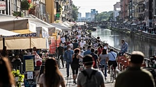 Des promeneurs profitent du soleil le long du canal Naviglio Grande à Milan le 24 mai 2020