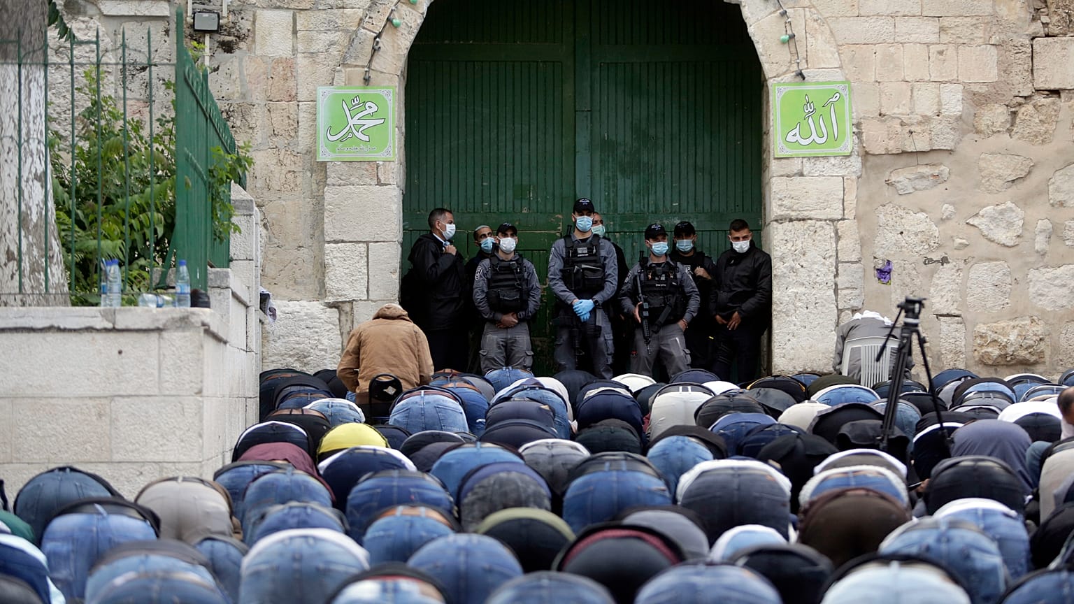 مصلون فلسطينيون ساجدون عند باب الأسباط المؤدي للمسجد الأقصى المغلق بسبب كورونا وأمامهم عناصر من القوات الخاصة في الشرطة الإسرائيلية