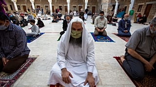 Musulmanes con máscaras faciales asisten a las oraciones de Eid al-Fitr fuera de una mezquita en la ciudad de Gaza, el 24 de mayo de 2020.