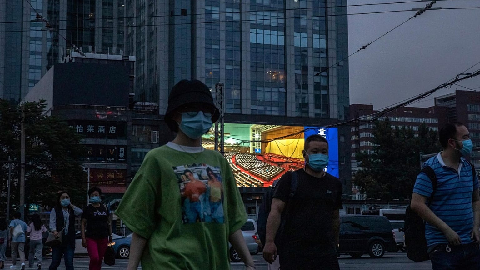 Des personnes marchent dans la rue alors qu'un écran géant diffuse des images du congrès national, Pékin le 22 mai 2020