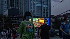 Des personnes marchent dans la rue alors qu'un écran géant diffuse des images du congrès national, Pékin le 22 mai 2020