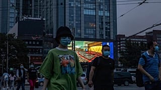 Des personnes marchent dans la rue alors qu'un écran géant diffuse des images du congrès national, Pékin le 22 mai 2020