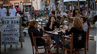 People drink as they sit on a terrace in Barcelona on Monday, May 25