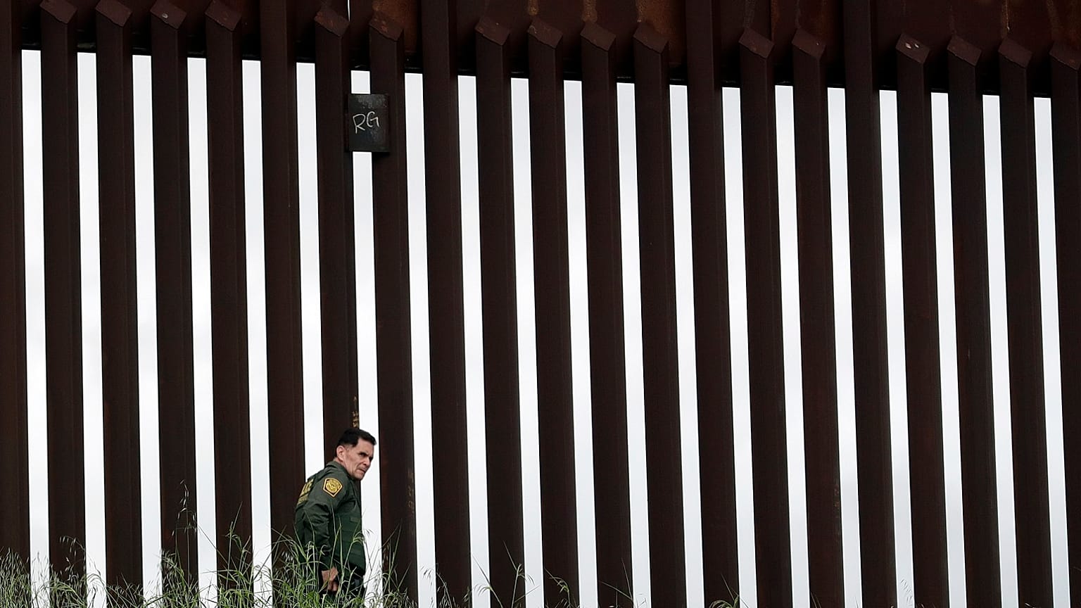 A border patrol agent walks along a border wall separating Tijuana, Mexico, from San Diego, Wednesday, March 18, 2020, in San Diego