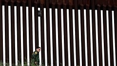 A border patrol agent walks along a border wall separating Tijuana, Mexico, from San Diego, Wednesday, March 18, 2020, in San Diego