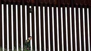 A border patrol agent walks along a border wall separating Tijuana, Mexico, from San Diego, Wednesday, March 18, 2020, in San Diego