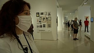Una joven con mascarilla observa una obra de arte en un museo de Málaga