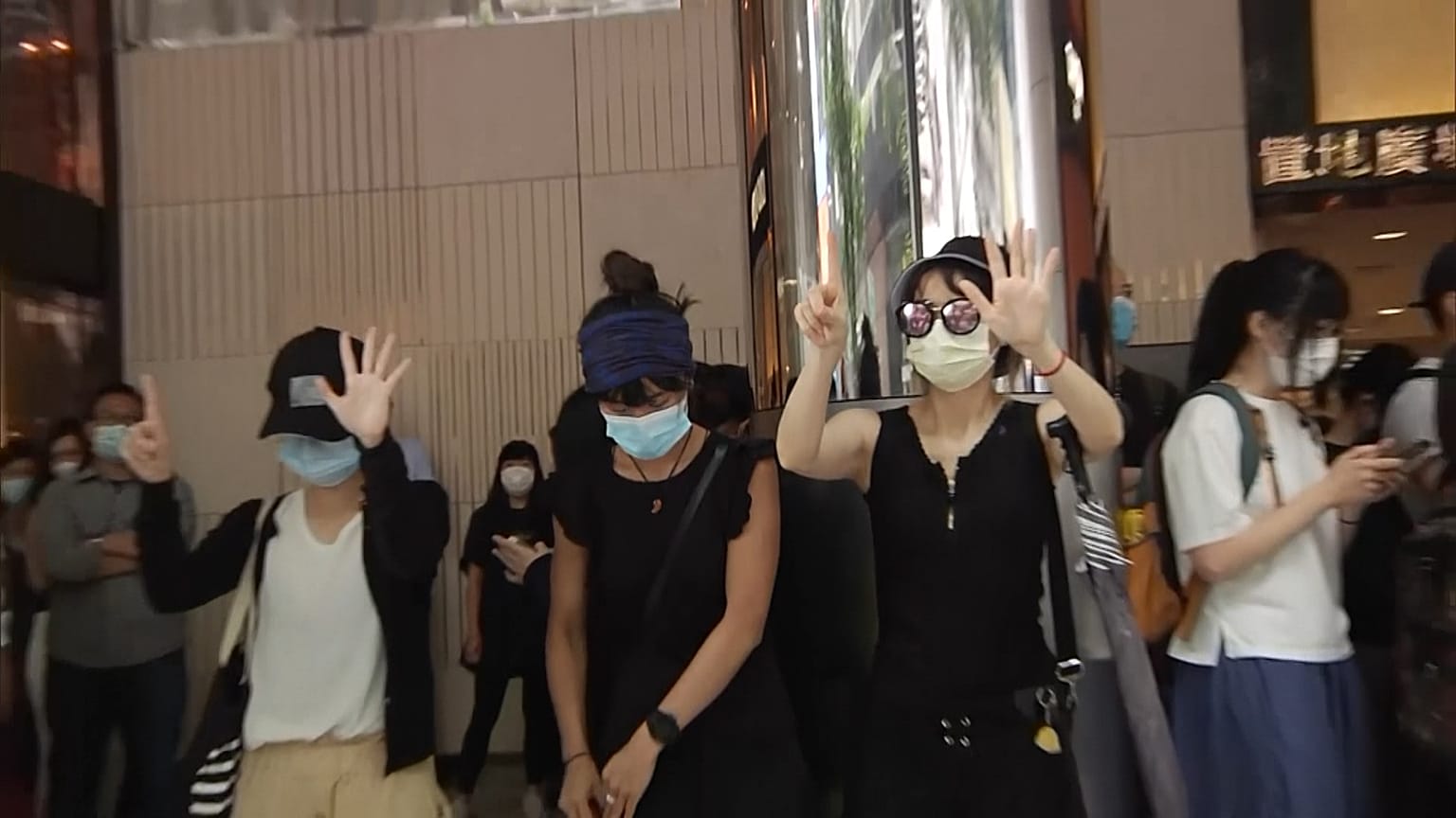 People protesting, holding up hands to signal protestor's demands