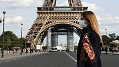 A woman wearing protective face mask walks next to the Eiffel Tower in Paris
