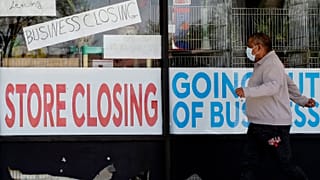 A man looks at signs of a closed store due to COVID-19 in Niles, Ill., Thursday, May 21, 2020.