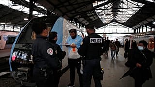 Police officers ask a man to put on his compulsory mask at the Saint Lazare train station