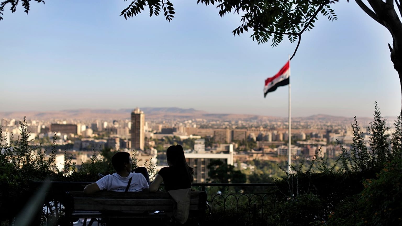 شاب ورفيقته يجلسان في حديقة عمومية مطلة على العاصمة السورية دمشق - 2019/07/24