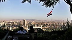 شاب ورفيقته يجلسان في حديقة عمومية مطلة على العاصمة السورية دمشق - 2019/07/24