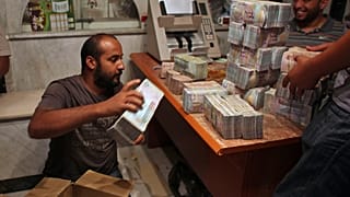 مواطن ليبي يعد رزم من الأموال في طرابلس