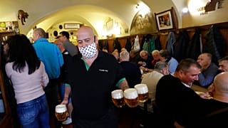 A waiter carries beer as a traditional beer pub opens in Prague, Czech Republic