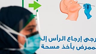 A technician prepares to take another nasal swab sample at a new coronavirus detection test at a drive-thru testing facility in Abu Dhabi