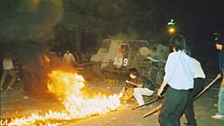 Student protesters put a barricade in front of a burning armored personnel carrier that rammed through student lines, June 4, 1989.