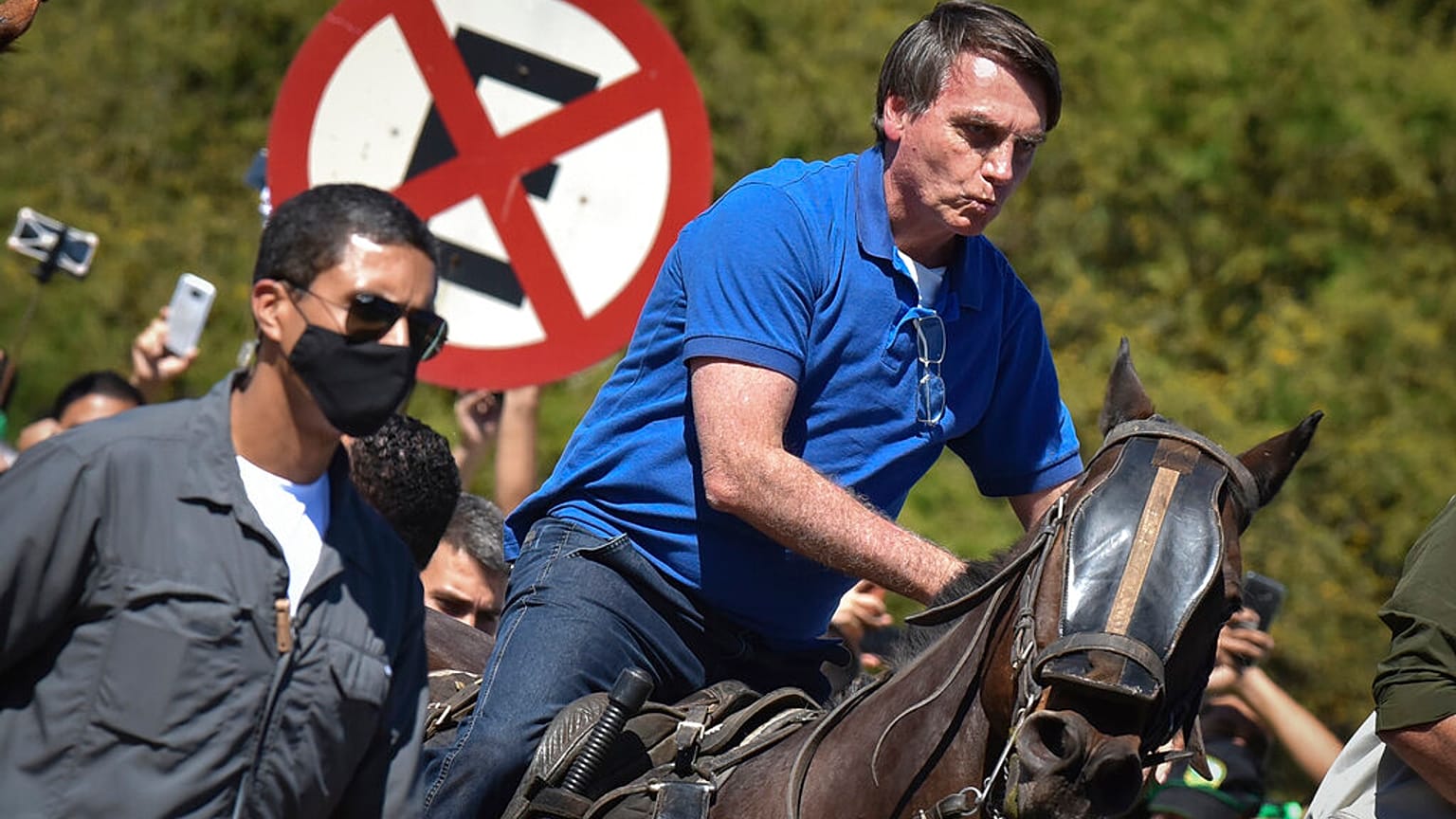 Brazil's President Jair Bolsonaro rides a horse greeting supporters outside the presidential palace in Brasilia, Brazil, Sunday, May 31, 2020. (AP Photo/Andre Borges)