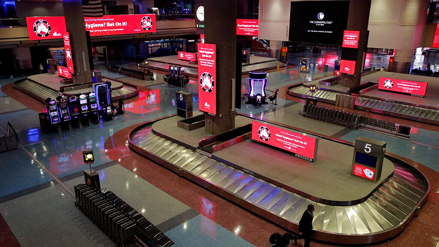 Ein Mann geht durch die Gepäckausgabe am Flughafen in Las Vegas, Freitag, 29. Mai 2020. Rot leuchten Schilder mit Hinweisen gegen Coronavirus-Infektionen.