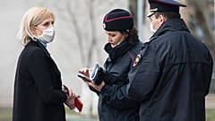 In this April 8, 2020, file photo, police officers check documents of a woman to ensure she is complying with a self-isolation regime due to coronavirus in Moscow, Russia