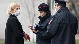 In this April 8, 2020, file photo, police officers check documents of a woman to ensure she is complying with a self-isolation regime due to coronavirus in Moscow, Russia