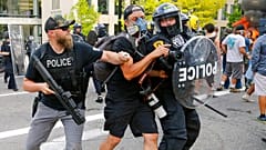 Agentes de policía empujan a un fotógrafo el sábado en Salt Lake City