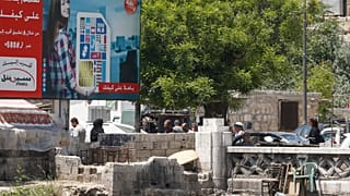 أناس يمشون في دمشق قرب لوحة إشهارية لأكبر مشغل للهواتف المحمولة في البلاد يملكها رامي مخلوف - 2020/05/11