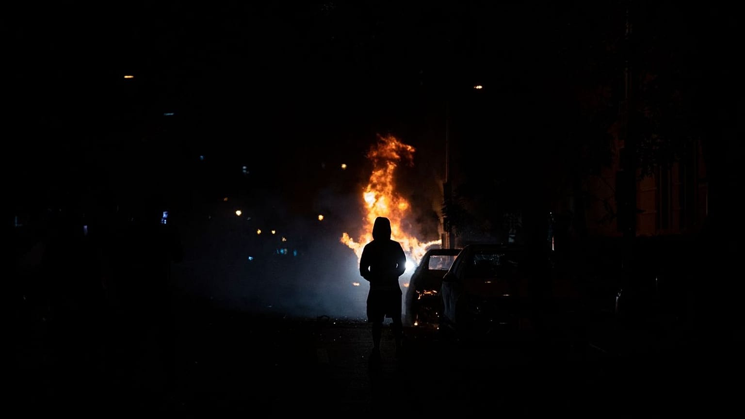 A demonstrator watches a car burn during protests over the death of George Floyd, near the White House in Washington, D.C.