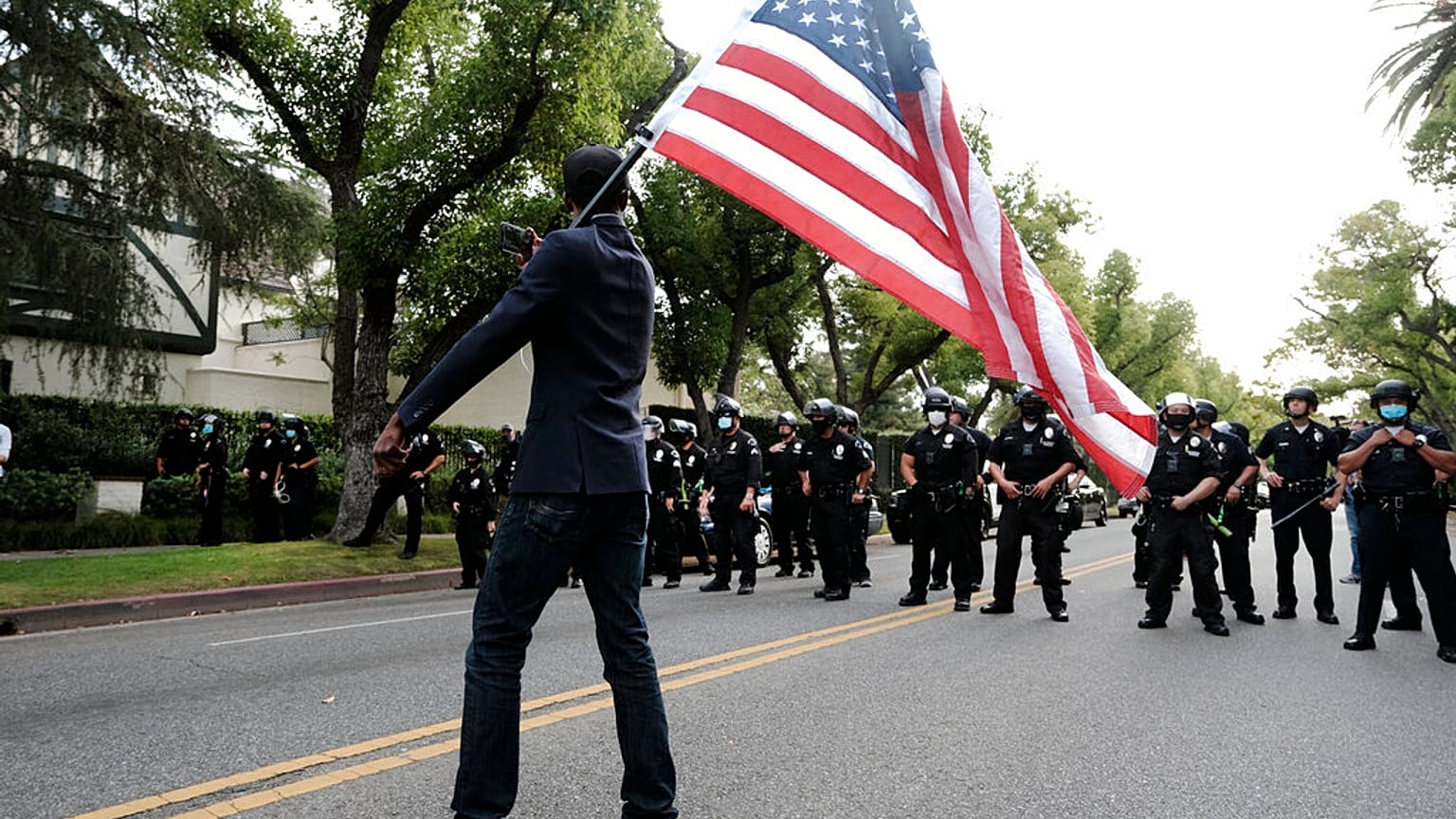 Un manifestante ondea una bandera ante policías en Los Ángeles