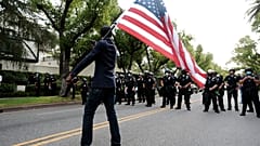 Un manifestante ondea una bandera ante policías en Los Ángeles