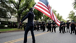 Un manifestante ondea una bandera ante policías en Los Ángeles