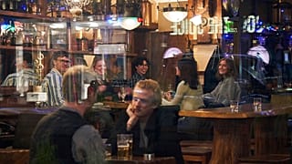People sit in a bar in Stockholm, Sweden, Wednesday, March 25, 2020. (AP Photo/David Keyton, File)