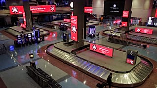 Un homme traverse la zone de récupération des bagages alors que des panneaux donnent des conseils pour prévenir la propagation du coronavirus à l'aéroport de Las Vegas.