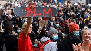 A protester holds up a skateboard with the Black Lives Matter initials in London, Wednesday, June 3, 2020 during a demonstration over the death of George Floyd.