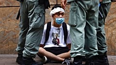 Riot police guard a protester as a second reading of a controversial national anthem law takes place in Hong Kong, Wednesday, May 27, 2020. 