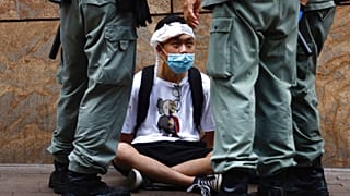 Riot police guard a protester as a second reading of a controversial national anthem law takes place in Hong Kong, Wednesday, May 27, 2020. 