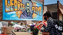 Malaysia Hammond, 19, places flowers at a memorial mural for George Floyd at the corner of Chicago Avenue and 38th Street, Sunday, May 31, 2020.