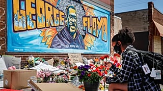 Malaysia Hammond, 19, places flowers at a memorial mural for George Floyd at the corner of Chicago Avenue and 38th Street, Sunday, May 31, 2020.
