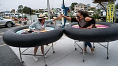 Restaurant guests use social distancing devices made of rubber tubing as Fish Tails Bar and Grill opens for in person dining during the pandemic. Ocean City, Maryland, USA 