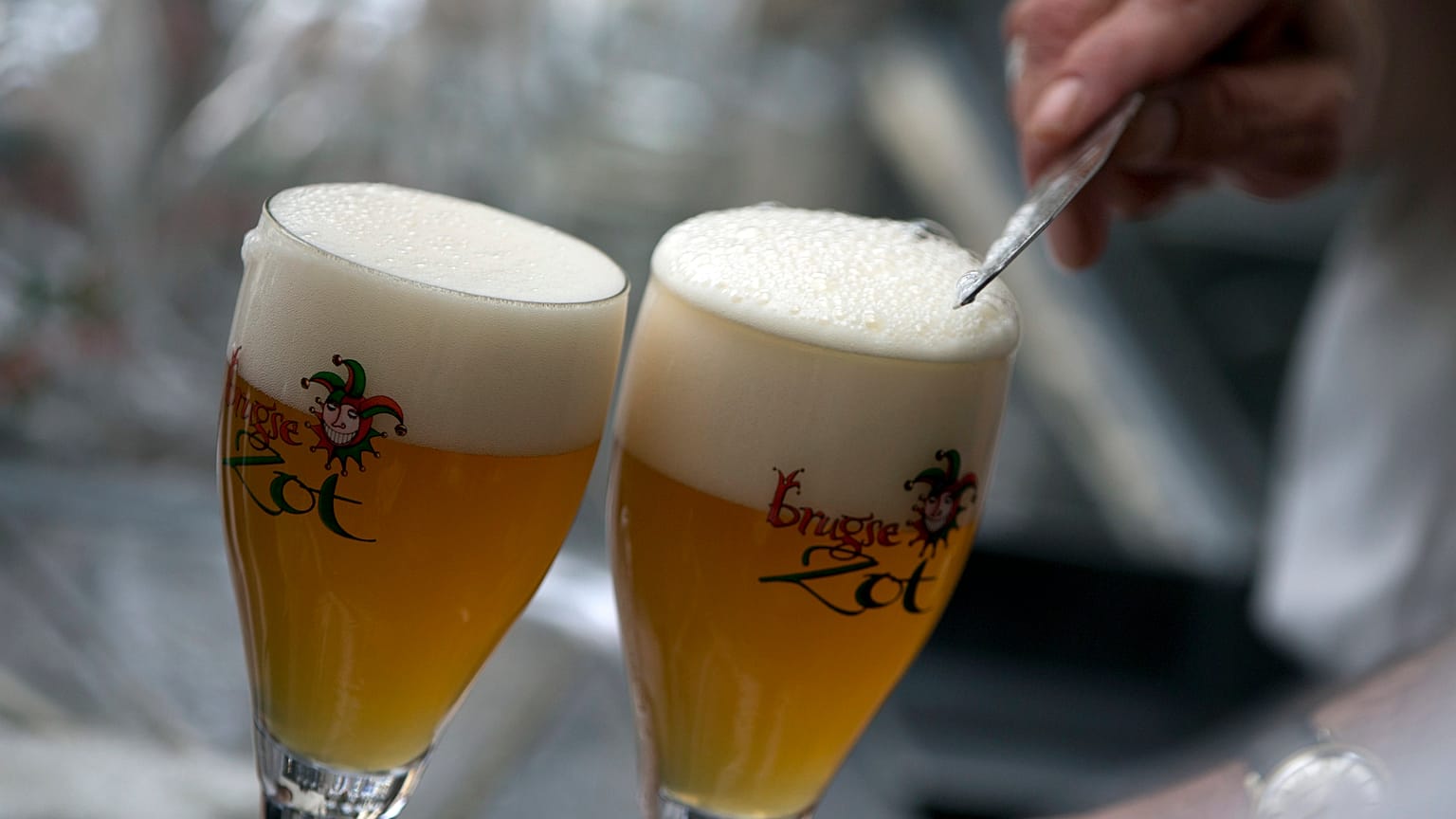 A worker scrapes the foam off of a glass of beer before serving, in Bruges, Belgium.