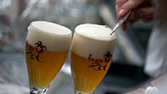 A worker scrapes the foam off of a glass of beer before serving, in Bruges, Belgium.