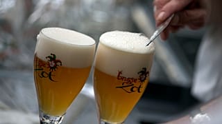 A worker scrapes the foam off of a glass of beer before serving, in Bruges, Belgium.