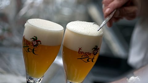A worker scrapes the foam off of a glass of beer before serving, in Bruges, Belgium.