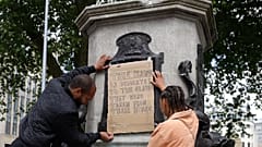 A banner is taped over the inscription on the pedestal of the toppled statue of Edward Colston in Bristol, England, Monday, June 8, 2020