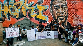 Protesters against police violence gather next to a new mural painted this week showing George Floyd with the Swahili word "Haki" meaning "Justice".
