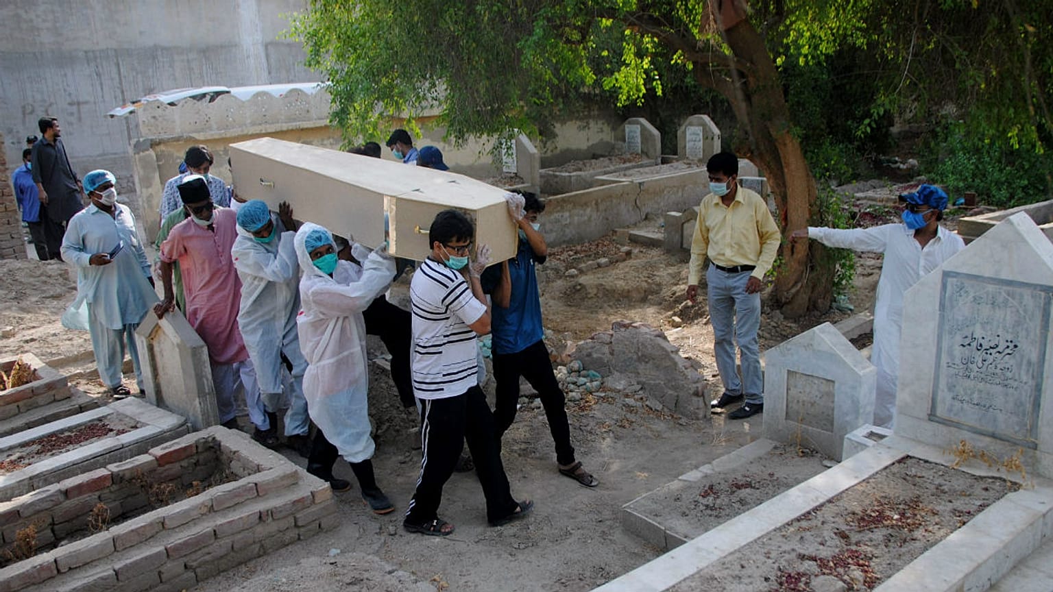 Rescue workers and family members carry the casket of Khursheed Bibi, who died due to coronavirus, for her burial at a cemetery in Hyderabad, Pakistan