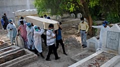 Rescue workers and family members carry the casket of Khursheed Bibi, who died due to coronavirus, for her burial at a cemetery in Hyderabad, Pakistan