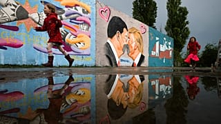 Graffiti depicts U.S. President Trump, right, and China's President Xi Jinping kissing each other with face masks on a wall in Berlin